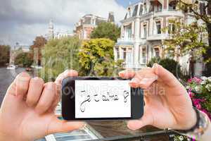 Composite image of hand holding smartphone showing je taime