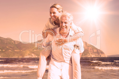 Man giving his laughing wife a piggy back at the beach Man giving his laughing wife a piggy back at the beach