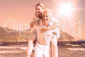 Man giving his laughing wife a piggy back at the beach