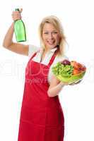 Frau präsentiert eine Salatschale und eine Flasche Essig