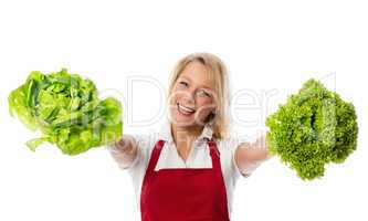 Blonde Frau mit Schürze zeigt Salatköpfe