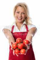 Frau mit Schürze präsentiert Handvoll Tomaten