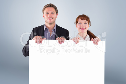 Composite image of smiling couple holding large sign