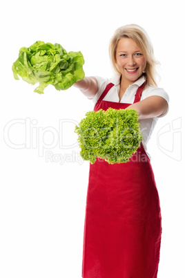 Blonde Frau mit Schürze zeigt Salatsorten
