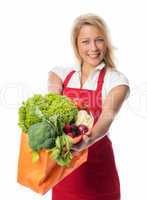 Blonde Frau mit Schürze hält Tasche voll Gemüse