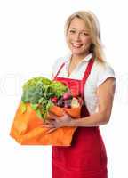 Blonde Frau mit Schürze hält Tasche voll Gemüse
