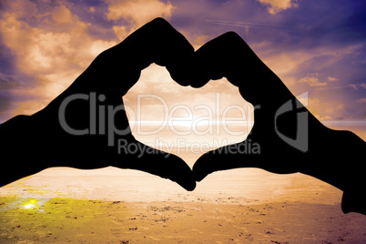 Composite image of couple making heart shape with hands