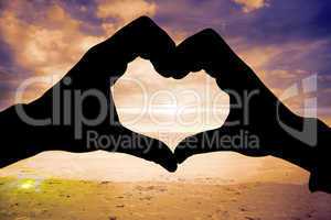 Composite image of couple making heart shape with hands