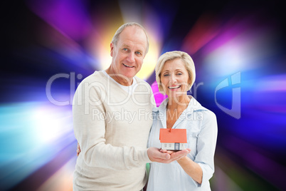 Composite image of happy mature couple with model house