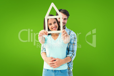 Composite image of happy young couple with house shape