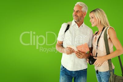 Composite image of happy tourist couple using the guidebook