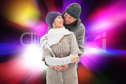 Composite image of happy mature couple in winter clothes embraci