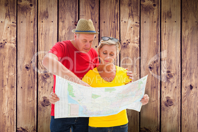 Composite image of lost tourist couple using map