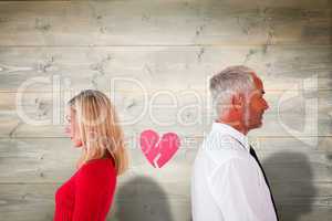 Composite image of couple not talking with broken heart between