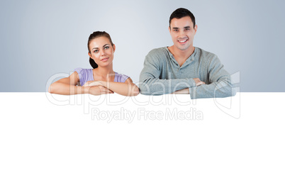 Composite image of smiling young couple looking over a wall