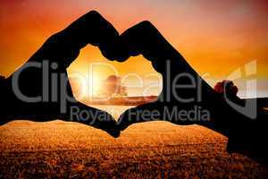 Composite image of couple making heart shape with hands