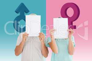 Composite image of couple holding paper over their faces