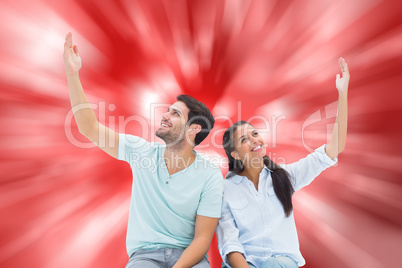 Composite image of cute couple sitting with arms raised