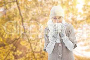 Composite image of woman in warm clothing holding mugs