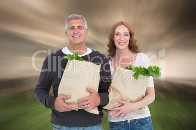 Composite image of casual couple holding grocery bags