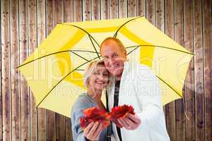 Composite image of happy mature couple showing autumn leaves und