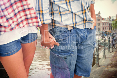 Composite image of couple in check shirts and denim holding hand