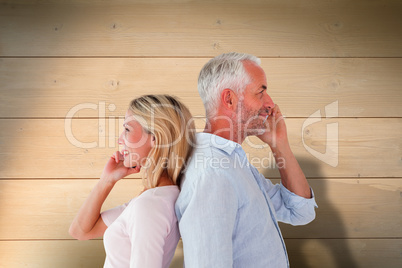 Composite image of happy couple talking on their smartphones