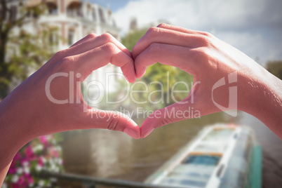 Composite image of hands making heart shape on the beach