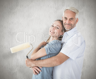 Composite image of happy couple hugging and holding paint roller Composite image of happy couple hugging and holding paint roller