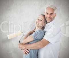 Composite image of happy couple hugging and holding paint roller