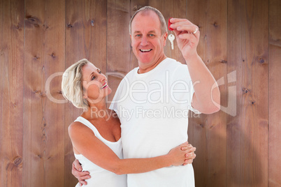 Composite image of mature couple smiling at camera with new hous