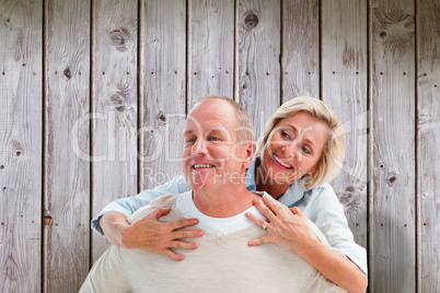 Composite image of happy mature man giving piggy back to partner