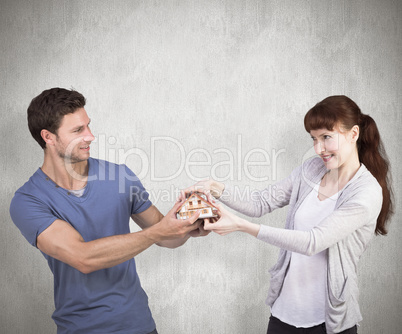 Composite image of couple pulling a model house