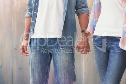 Composite image of hip young couple holding hands