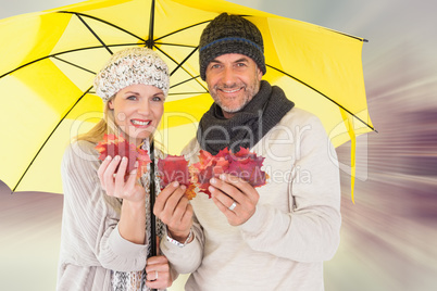 Composite image of couple in winter fashion showing autumn leave