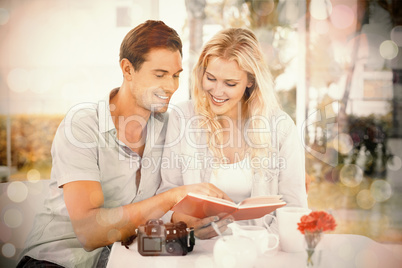 Cute hipster couple reading book together at table