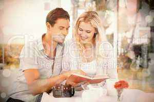 Cute hipster couple reading book together at table