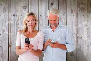 Composite image of happy couple texting on their smartphones