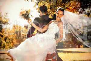 Newlywed couple sitting on scooter in park