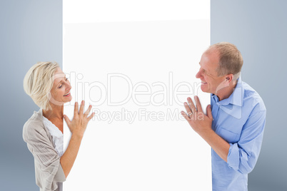 Composite image of mature couple smiling and holding card