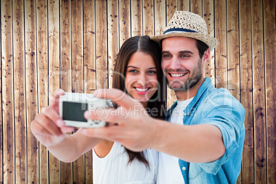 Composite image of happy hipster couple taking a selfie