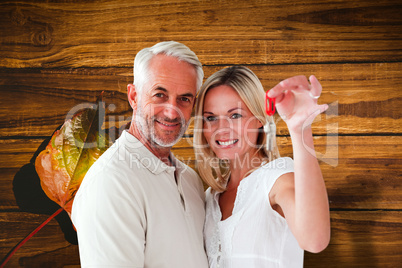 Composite image of happy couple showing their new house key