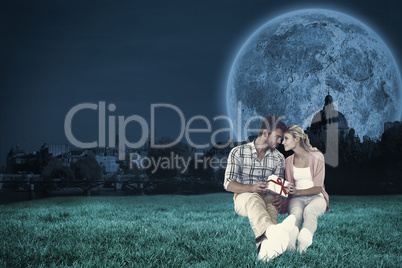 Composite image of attractive young couple sitting holding a gif