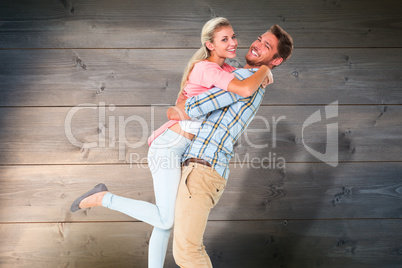 Composite image of handsome man picking up and hugging his girlf