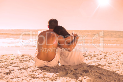 Couple sitting on the sand watching the sea