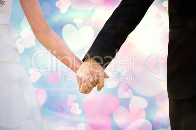 Composite image of mid section of newlywed couple holding hands