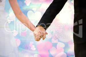 Composite image of mid section of newlywed couple holding hands