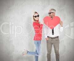 Composite image of cool couple holding a red heart together