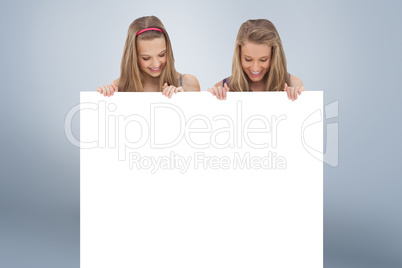 Composite image of close up of two young women holding a blank b