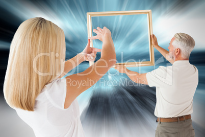 Composite image of couple hanging a frame together